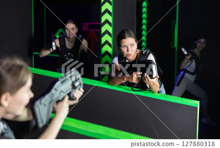 Laser tag players cheerful positive smiling girls playing in teams in laser tag room 127880318
