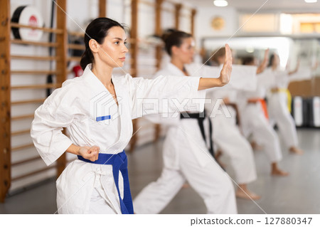 Women practice fighting stances during karate 127880347