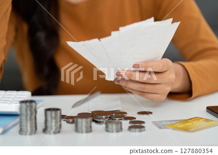 Money Management and Financial Planning. Woman counting coins while reviewing bills. 127880354
