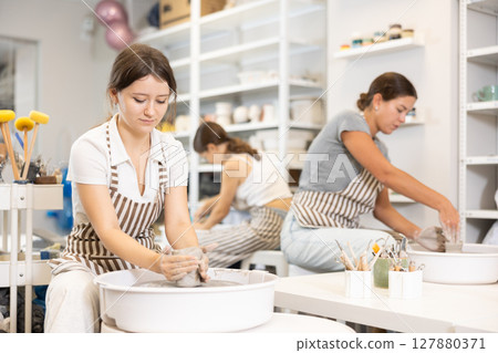 Woman teacher and students make products on potter's wheel 127880371