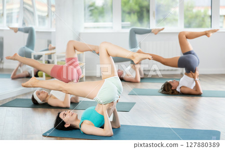 Together with coach, girls perform inverted asanas, move from lying position to plow asana 127880389