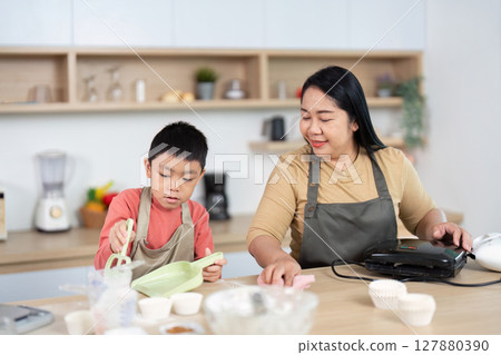 Cleaning and Baking. Mother and child sharing laughter while preparing in the kitchen. 127880390
