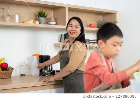 Kitchen Cleaning Collaboration. An adult and child working together in the kitchen. Kitchen Cleaning Collaboration. An adult and child working together in the kitchen. 127880393