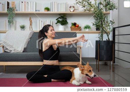 Mindful Yoga with Dog. Woman enjoying yoga poses with her corgi companion at home. 127880559