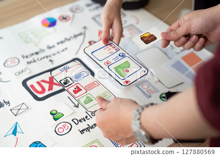 Collaborative UX Design. Team members discussing user interface elements on design board. Collaborative UX Design. Team members discussing user interface elements on design board. 127880569