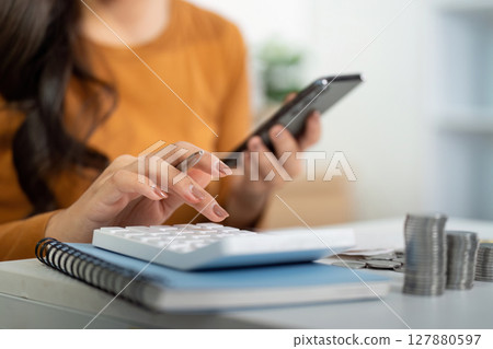 Financial Planning and Budgeting. Woman calculating expenses using smartphone and calculator. Financial Planning and Budgeting. Woman calculating expenses using smartphone and calculator. 127880597