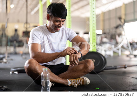 Fitness and Wellness. Young man checking smartwatch after workout in gym. 127880657