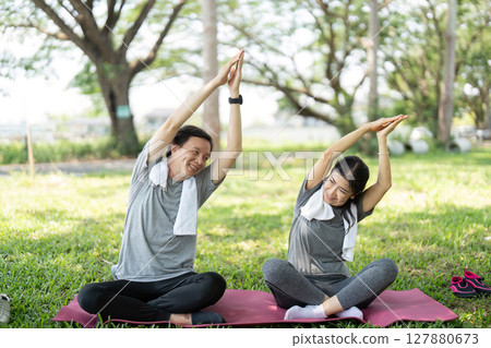 Couple enjoying outdoor yoga stretches in a park 127880673