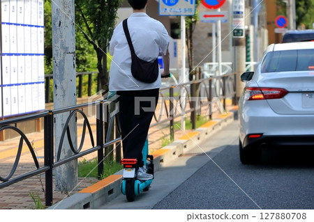 An electric kick scooter running on the road 127880708