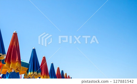 Bright beach umbrellas and wide blue skies Bright beach umbrellas and wide blue skies 127881542