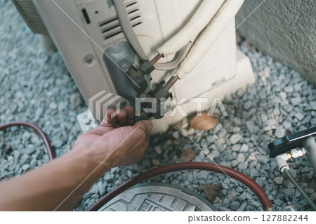 用手暫時鎖緊空調室外機維修口的蓋子。 127882244