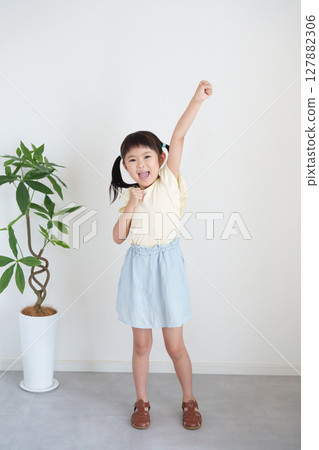 A child's whole body doing a fist pump 127882306