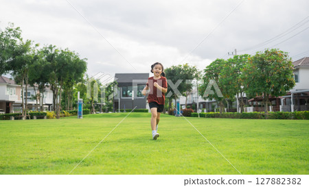 Happy child running joyfully in a lush green park, enjoying a sunny day of outdoor fun, showcasing freedom, energy, and vibrant childhood moments 127882382
