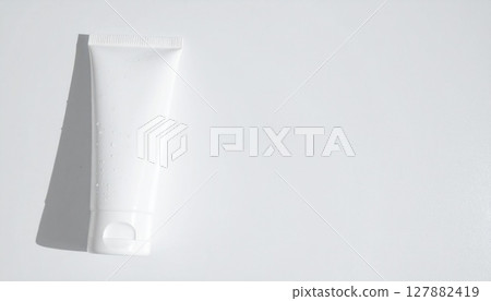 Facial cleanser container with water droplets on a matte white background 127882419
