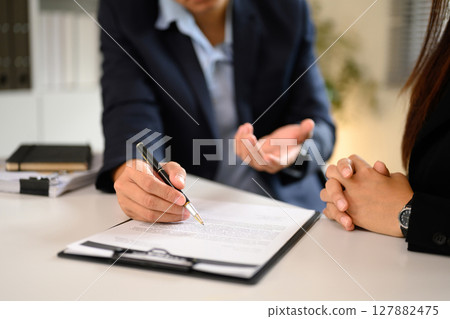 Professional agreement signing between client and business agent in modern office Professional agreement signing between client and business agent in modern office 127882475