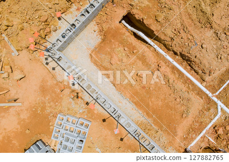 Workers are digging out trench for plumbing installation at construction site in works foundation area 127882765
