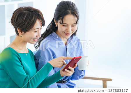 兩位女士在現代客廳看智慧型手機 127883127