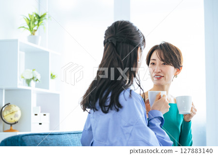 Two women relaxing in a modern living room 127883140