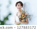 一位身穿白色洋裝的女子手捧一束乾燥花 127883172
