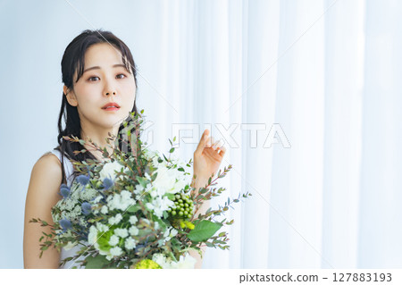 A woman in a white dress holding a natural bouquet 127883193