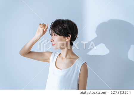 A woman in a white dress bathed in light 127883194