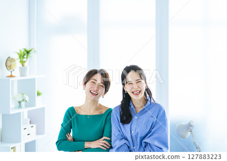 Two women standing close together in a modern office Two women standing close together in a modern office 127883223