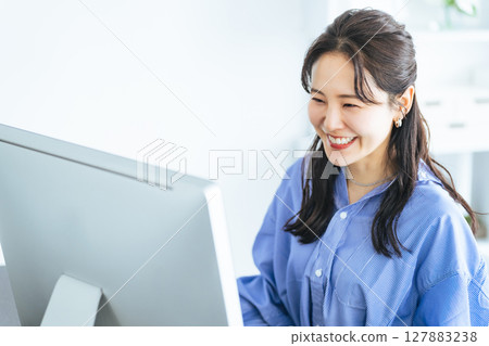 A woman working while looking at a PC monitor in a modern office A woman working while looking at a PC monitor in a modern office 127883238