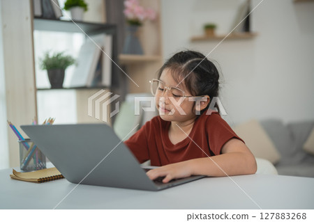 Young girl working on laptop at home, focused on homework or online learning, cozy environment with plants and soft lighting Young girl working on laptop at home, focused on homework or online learning, cozy environment with plants and soft lighting 127883268