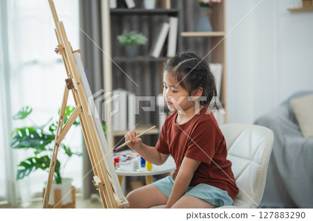 Young girl artist painting on easel in bright room filled with plants and natural light, showcasing creativity and passion for art expression Young girl artist painting on easel in bright room filled with plants and natural light, showcasing creativity and passion for art expression 127883290