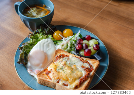 A Western-style breakfast plate with cheese toast, fried egg, and salad 127883463