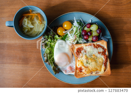 A Western-style breakfast plate with cheese toast, fried egg, and salad 127883470