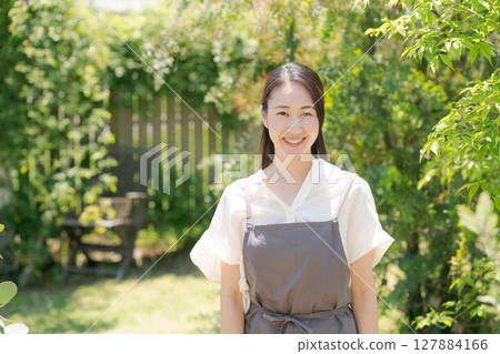 一位穿著圍裙的女人站在花園裡 127884166