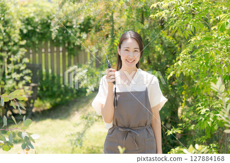 A woman in an apron standing in a garden 127884168