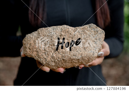 Woman hand holding stone with word hope engraved concept for faith, love, spirituality, religion. Happy female being thankful. Spiritual girl praying with hope. Positive asian young woman feeling hope Woman hand holding stone with word hope engraved concept for faith, love, spirituality, religion. Happy female being thankful. Spiritual girl praying with hope. Positive asian young woman feeling hope 127884196
