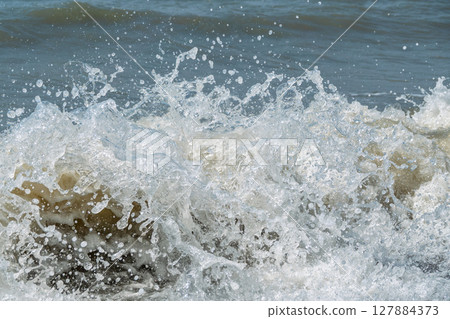 Sea water splashing over the stones on the beach Sea water splashing over the stones on the beach 127884373