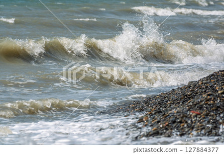 Sea water splashing over the stones on the beach Sea water splashing over the stones on the beach 127884377