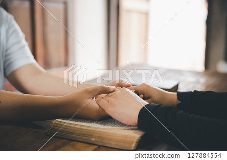 Praying religion, worship and group of people pray to God, Family, holding hands and prayer in home for love, support and faith or hope in house. holy spirit or Jesus for peace or spiritual praise. 127884554