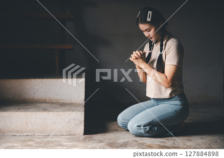 Female kneeling down praying for worship God at home. Christians pray to jesus christ for calmness. people got to quiet place and worship. Christians humble and submit to God. Banner with copy space. 127884898