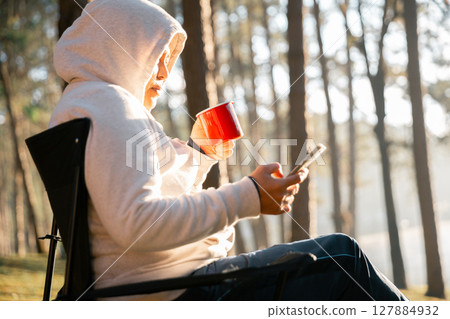 Remote work technology online close up communication smart phone laptop telephone digital travel brown nature sunlight camp beverage morning sit drink coffee tent orange outlying concept background. 127884932