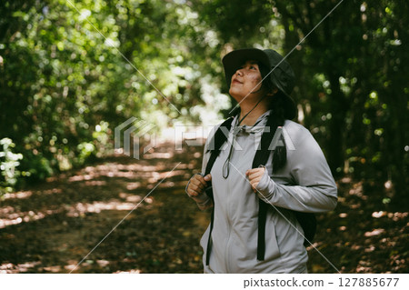 Young female traveler with backpack walking in national park or forest. recreation sport in nature. Female person bag, wave for hiking journey in woods. adventure in forest. trekking with backpack Young female traveler with backpack walking in national park or forest. recreation sport in nature. Female person bag, wave for hiking journey in woods. adventure in forest. trekking with backpack 127885677