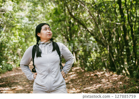 Young female traveler with backpack walking in national park or forest. recreation sport in nature. Female person bag, wave for hiking journey in woods. adventure in forest. trekking with backpack 127885759