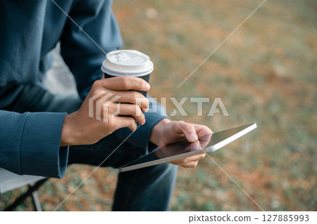 Remote work technology online close up communication smart phone laptop telephone digital travel brown nature sunlight camp beverage morning sit drink coffee tent orange outlying concept background. Remote work technology online close up communication smart phone laptop telephone digital travel brown nature sunlight camp beverage morning sit drink coffee tent orange outlying concept background. 127885993