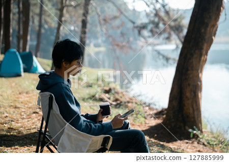 Remote work technology online close up communication smart phone laptop telephone digital travel brown nature sunlight camp beverage morning sit drink coffee tent orange outlying concept background. 127885999