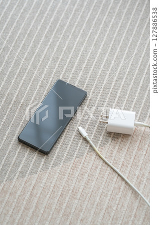 A composition with a smartphone and AC adapter placed on the floor 127886538