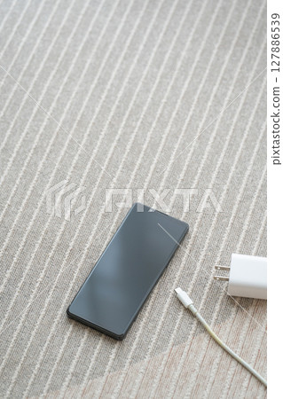 智慧型手機和 AC 適配器放置在地板上的構圖 127886539
