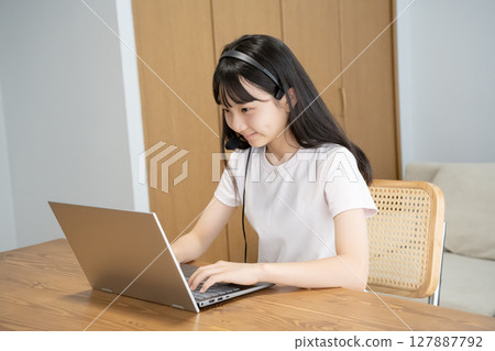 一個戴著耳機操作電腦的女孩 127887792