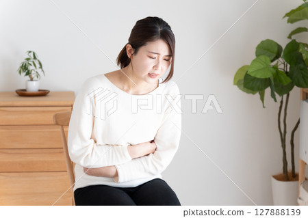 A woman holding her stomach with stomachache A woman holding her stomach with stomachache 127888139