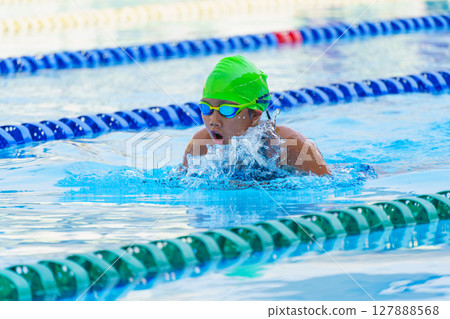 Swimmer child swims breaststroke swimming style in a race swimming pool. Water sports and competition, learning to swim classes for children. Swimmer child swims breaststroke swimming style in a race swimming pool. Water sports and competition, learning to swim classes for children. 127888568