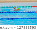 Swimmer child swims freestyle swimming style in a race swimming pool. Water sports and competition, learning to swim classes for children. 127888593