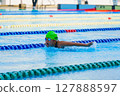 Swimmer child swims butterfly swimming style in a race swimming pool. Water sports and competition, learning to swim classes for children. 127888597